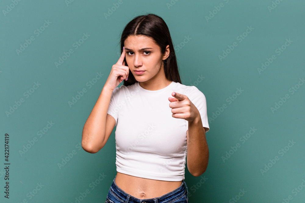 Young Indian woman isolated on blue background pointing temple with finger, thinking, focused on a task.