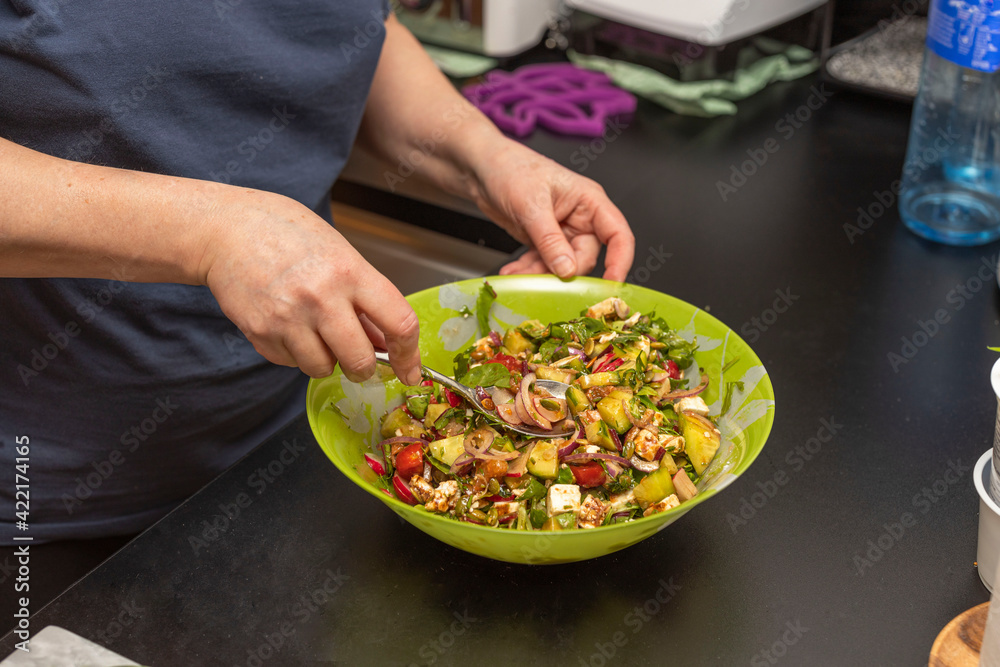 Close up view of woman making healthy green salad bowl. 
