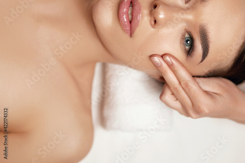 Face massage. Beautiful of young woman getting spa massage treatment at beauty spa salon.Spa skin and body care. Facial beauty treatment.Cosmetology.