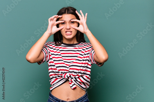 Young Indian woman isolated on blue background keeping eyes opened to find a success opportunity.