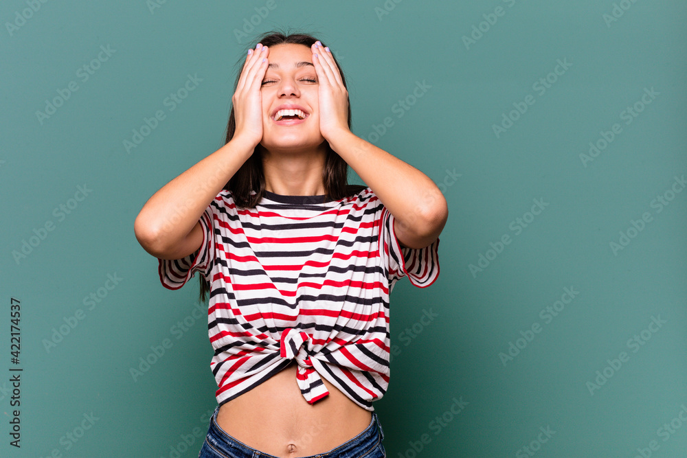 Young Indian woman isolated on blue background laughs joyfully keeping hands on head. Happiness concept. Young Indian woman isolated on blue background laughs joyfully keeping hands on head. Happiness concept.