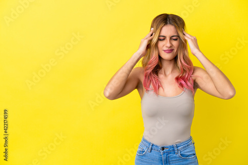 Young woman over isolated yellow background with headache