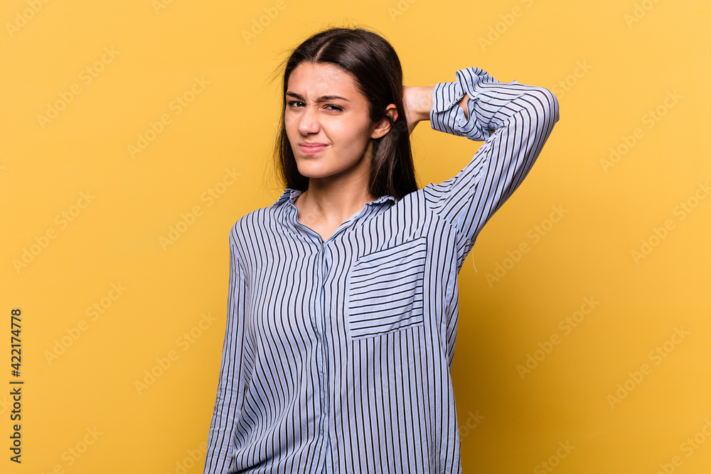Young Indian woman isolated on yellow background suffering neck pain due to sedentary lifestyle. Young Indian woman isolated on yellow background suffering neck pain due to sedentary lifestyle.