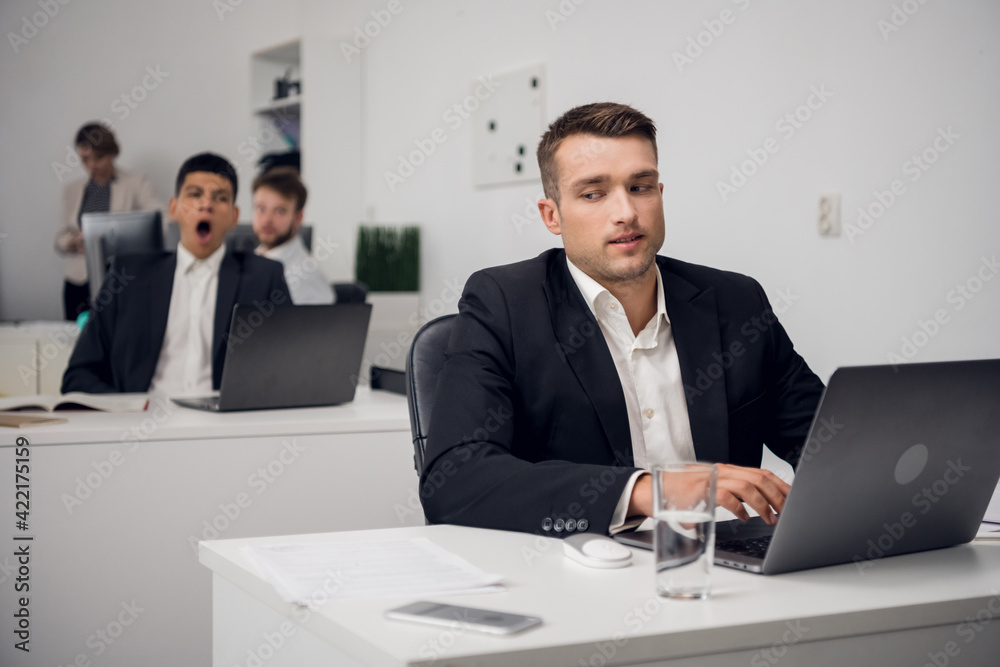 Two managers of a carsharing company are engaged in routine business in the office in a laptop. They are distracted from their work. Two managers of a carsharing company are engaged in routine business in the office in a laptop. They are distracted from their work.