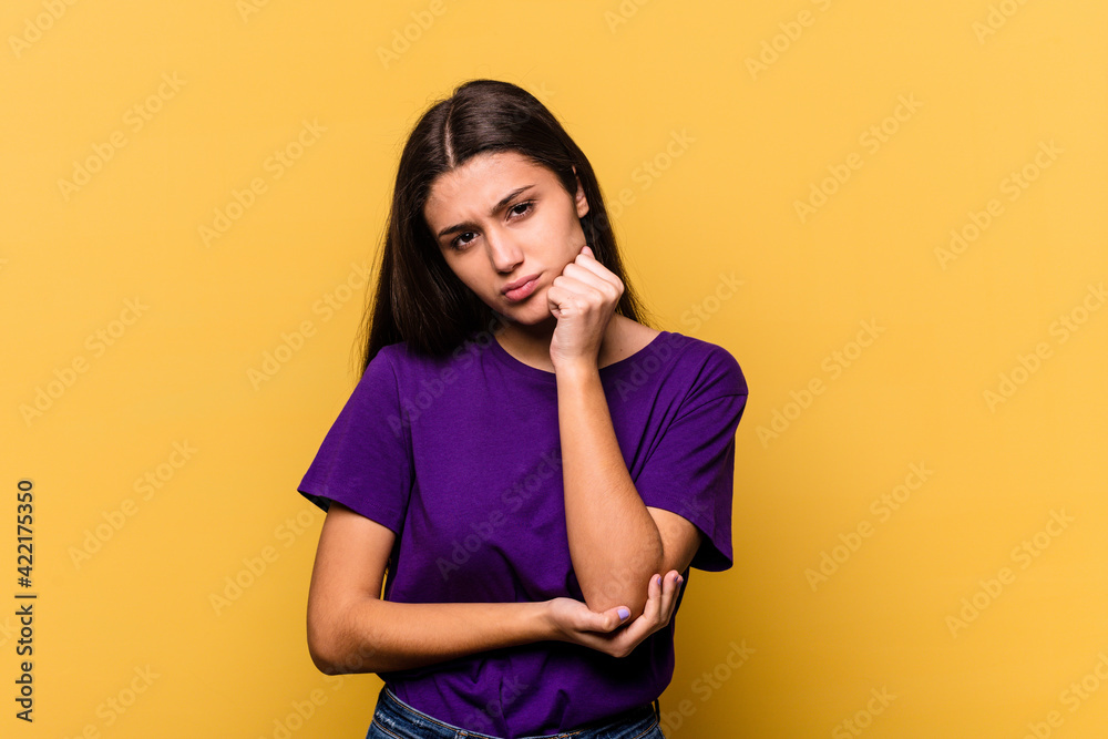 Young Indian woman isolated on yellow background tired of a repetitive task. Young Indian woman isolated on yellow background tired of a repetitive task.