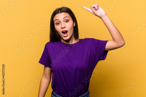 Young Indian woman isolated on yellow background having some great idea, concept of creativity.