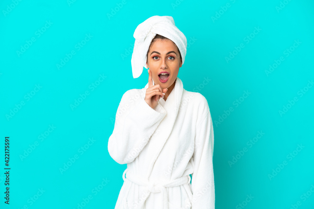 Young woman in a bathrobe over isolated blue background intending to realizes the solution while lifting a finger up Young woman in a bathrobe over isolated blue background intending to realizes the solution while lifting a finger up