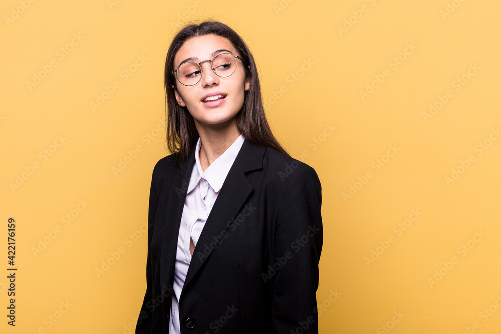 Young Indian business woman isolated on yellow background looks aside smiling, cheerful and pleasant. Young Indian business woman isolated on yellow background looks aside smiling, cheerful and pleasant.