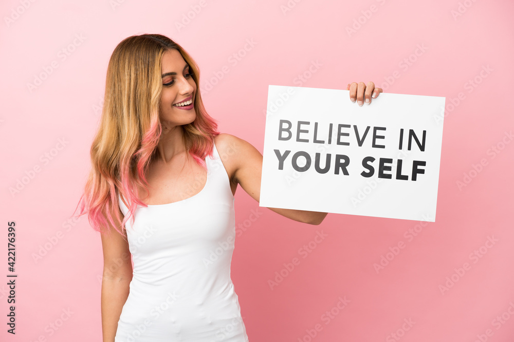 Young woman over isolated pink background holding a placard with text Believe In Your Self Young woman over isolated pink background holding a placard with text Believe In Your Self