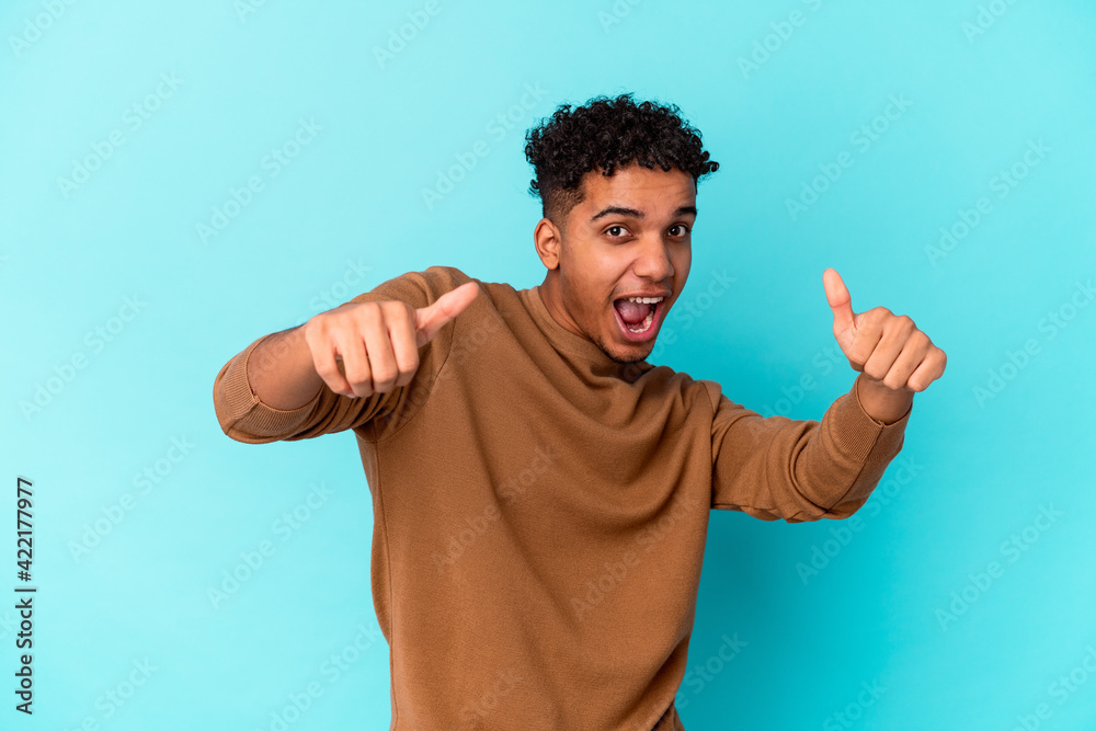 Young african american curly man isolated on blue raising both thumbs up, smiling and confident. Young african american curly man isolated on blue raising both thumbs up, smiling and confident.
