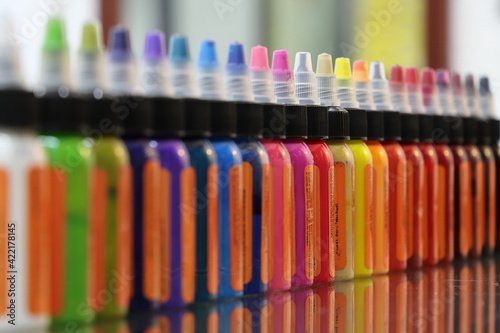 Tintas de colores en envases de pl  stico formadas en una fila y fondo bokeh