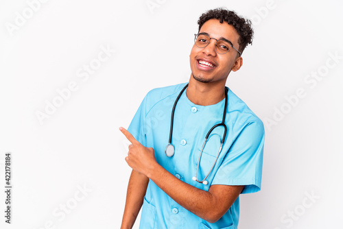 Young african american curly nurse man isolated smiling and pointing aside, showing something at blank space.