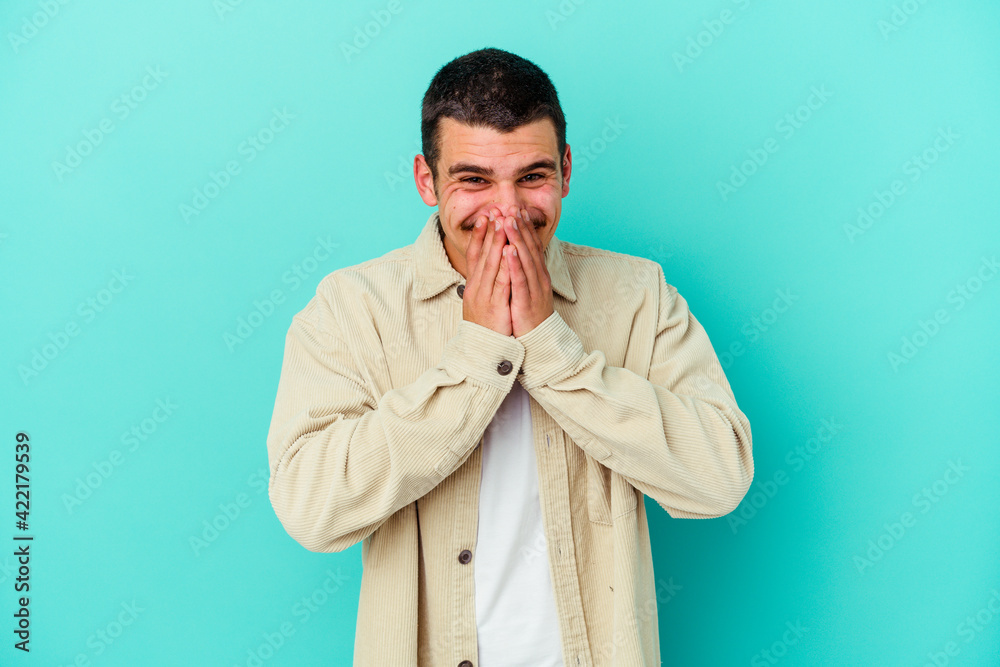 Young caucasian man isolated on blue background laughing about something, covering mouth with hands. Young caucasian man isolated on blue background laughing about something, covering mouth with hands.