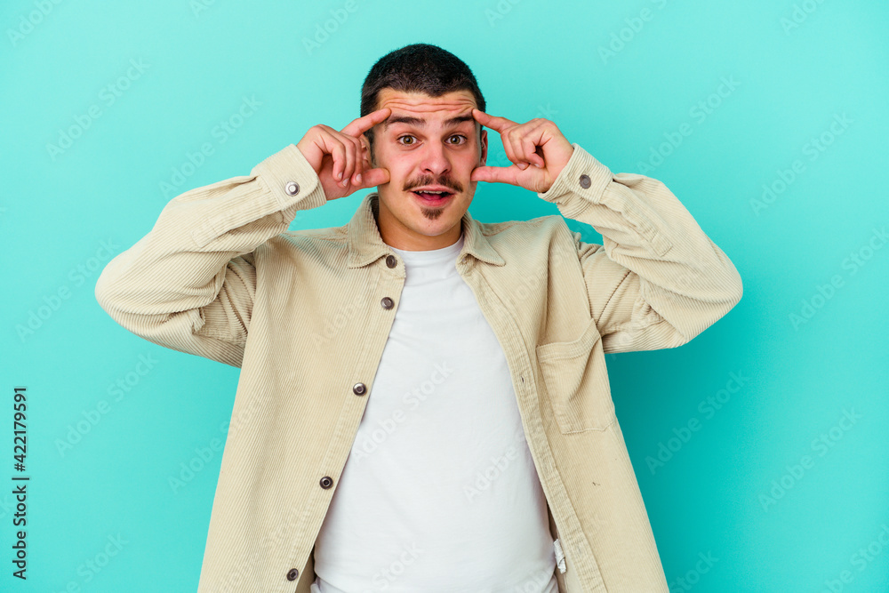 Young caucasian man isolated on blue background keeping eyes opened to find a success opportunity. Young caucasian man isolated on blue background keeping eyes opened to find a success opportunity.