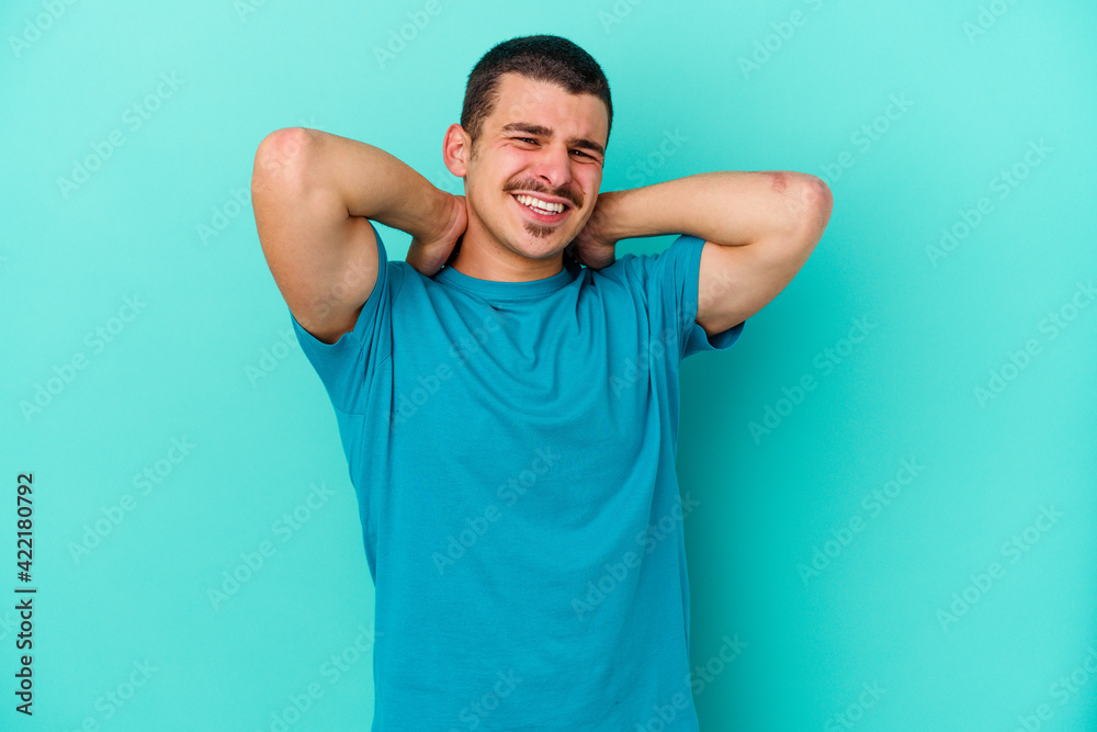 Young caucasian man isolated on blue background suffering neck pain due to sedentary lifestyle. Young caucasian man isolated on blue background suffering neck pain due to sedentary lifestyle.