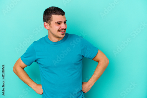 Young caucasian man isolated on blue background dreaming of achieving goals and purposes