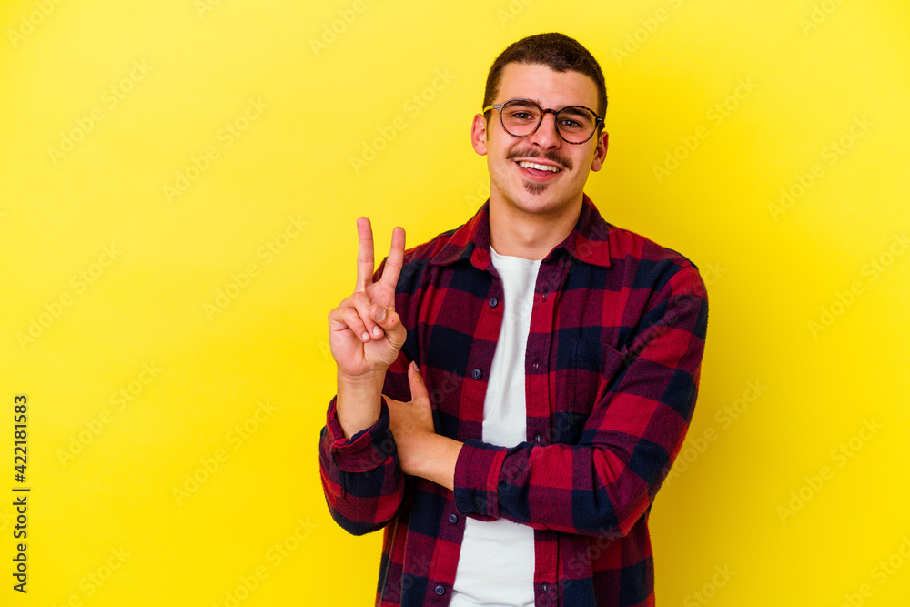Young caucasian cool man isolated on yellow background showing number two with fingers. Young caucasian cool man isolated on yellow background showing number two with fingers.