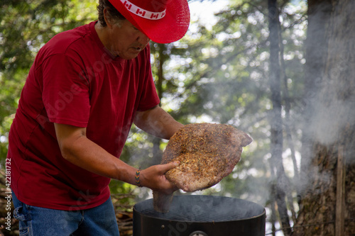 mans hands placing a large beef brisket on a smoker