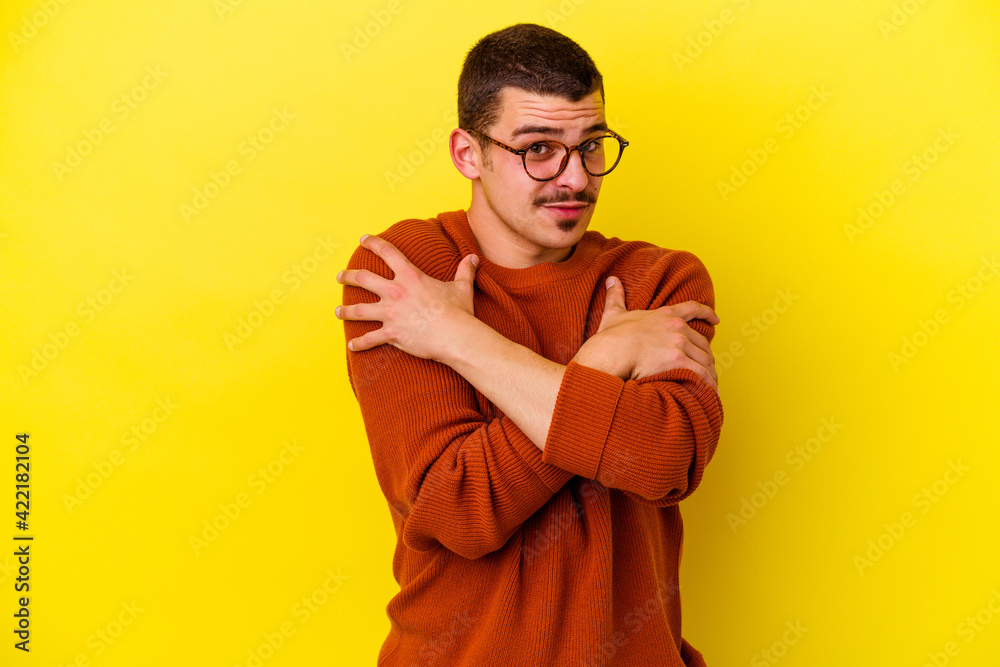 Fototapeta premium Young caucasian cool man isolated on yellow background hugs, smiling carefree and happy.