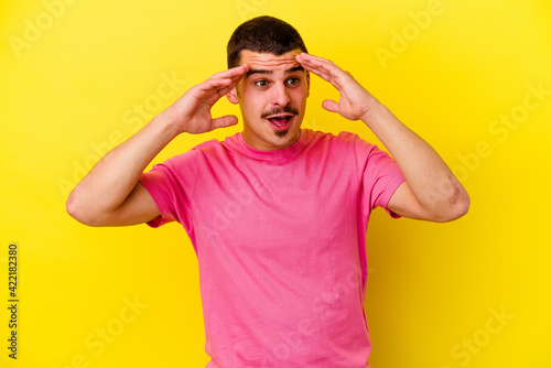 Young caucasian cool man isolated on yellow background receiving a pleasant surprise, excited and raising hands.