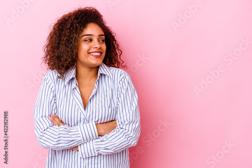 Young african american woman isolated on pink background smiling confident with crossed arms.