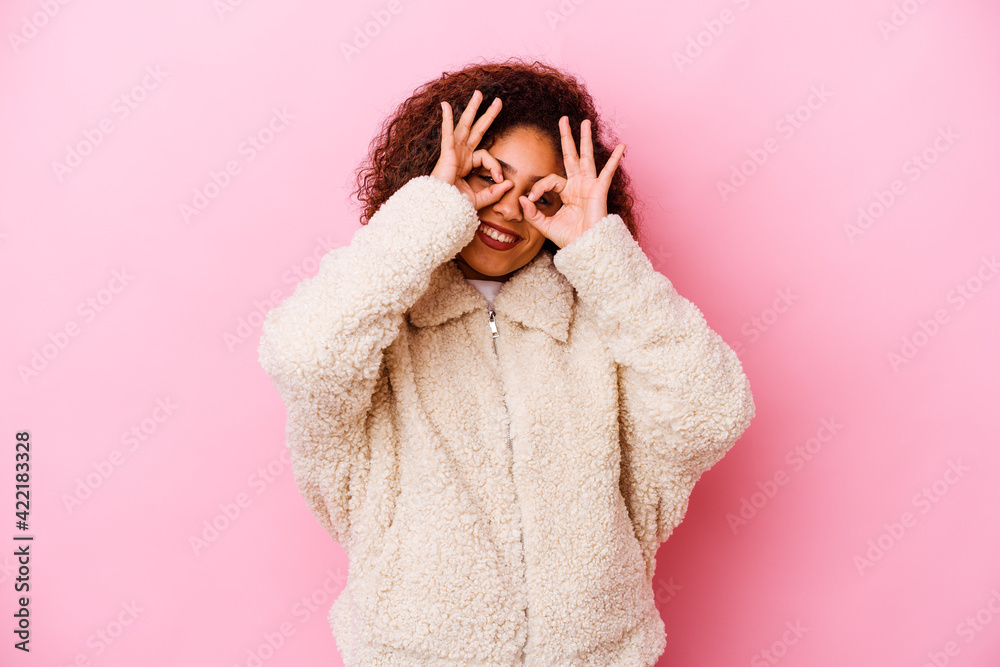 Young african american woman isolated on pink background showing okay sign over eyes Young african american woman isolated on pink background showing okay sign over eyes