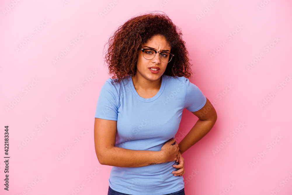 Young african american woman isolated on pink background having a liver pain, stomach ache.