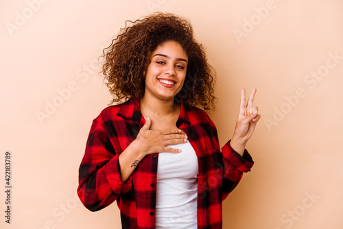 Bild auf Leinwand Young african american woman isolated on beige background taking an oath, putting hand on chest