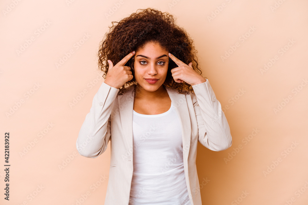 Young african american woman isolated on beige background focused on a task, keeping forefingers pointing head. Young african american woman isolated on beige background focused on a task, keeping forefingers pointing head.
