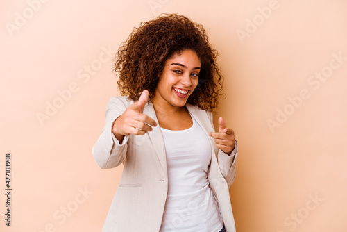 Young african american woman isolated on beige background cheerful smiles pointing to front.