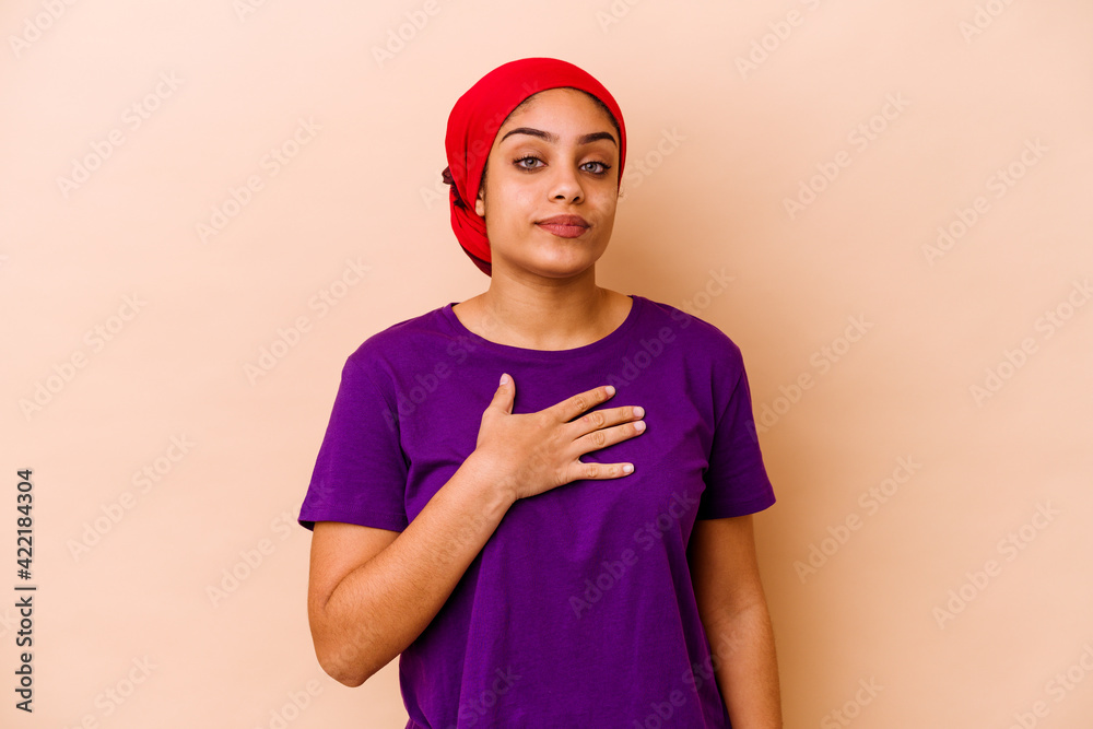 Young african american woman isolated on beige background taking an oath, putting hand on chest. Young african american woman isolated on beige background taking an oath, putting hand on chest.