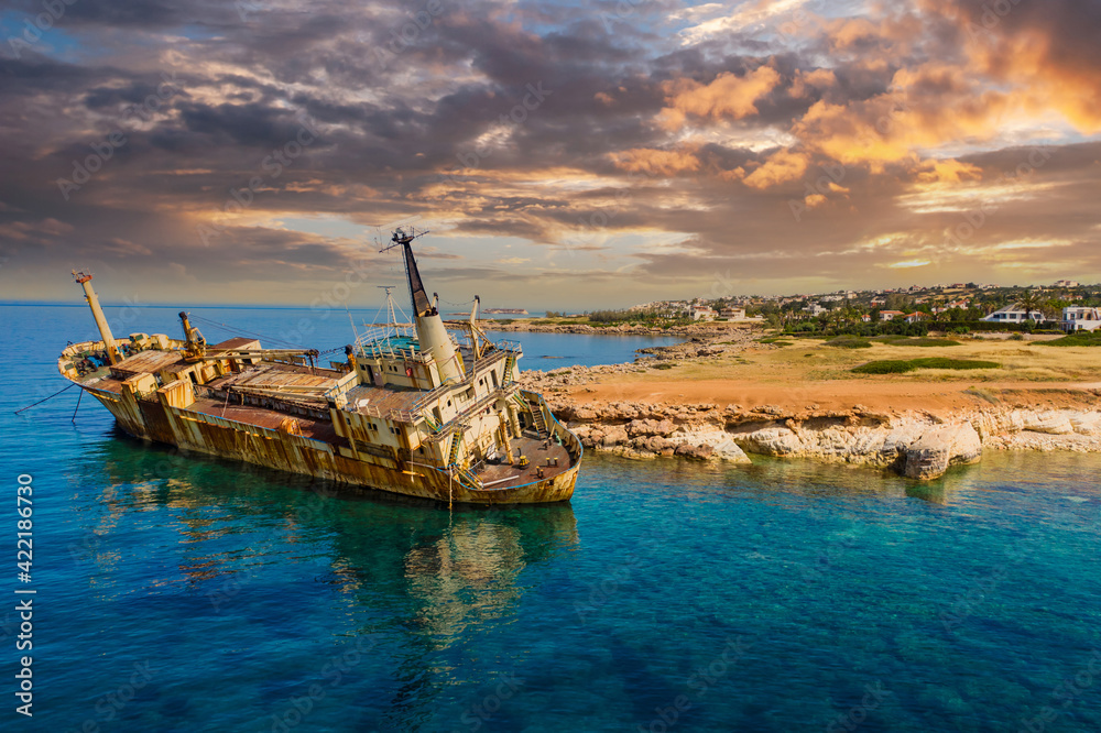 Old ship off coast of Cyprus. Abandoned ship near city of Paphos. Sights of beaches of Cyprus. Rusty ship off Mediterranean coast. Paphos city in background. Holidays in Cyprus.