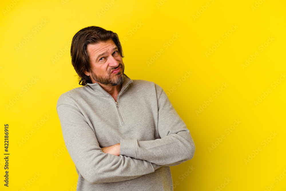 Middle age caucasian man isolated on yellow background suspicious, uncertain, examining you. Middle age caucasian man isolated on yellow background suspicious, uncertain, examining you.