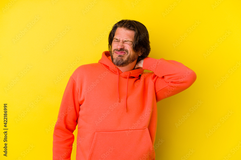 Middle age caucasian man isolated on yellow background having a neck pain due to stress, massaging and touching it with hand. Middle age caucasian man isolated on yellow background having a neck pain due to stress, massaging and touching it with hand.