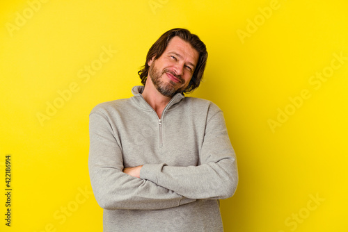 Middle age caucasian man isolated on yellow background who feels confident, crossing arms with determination. © Asier