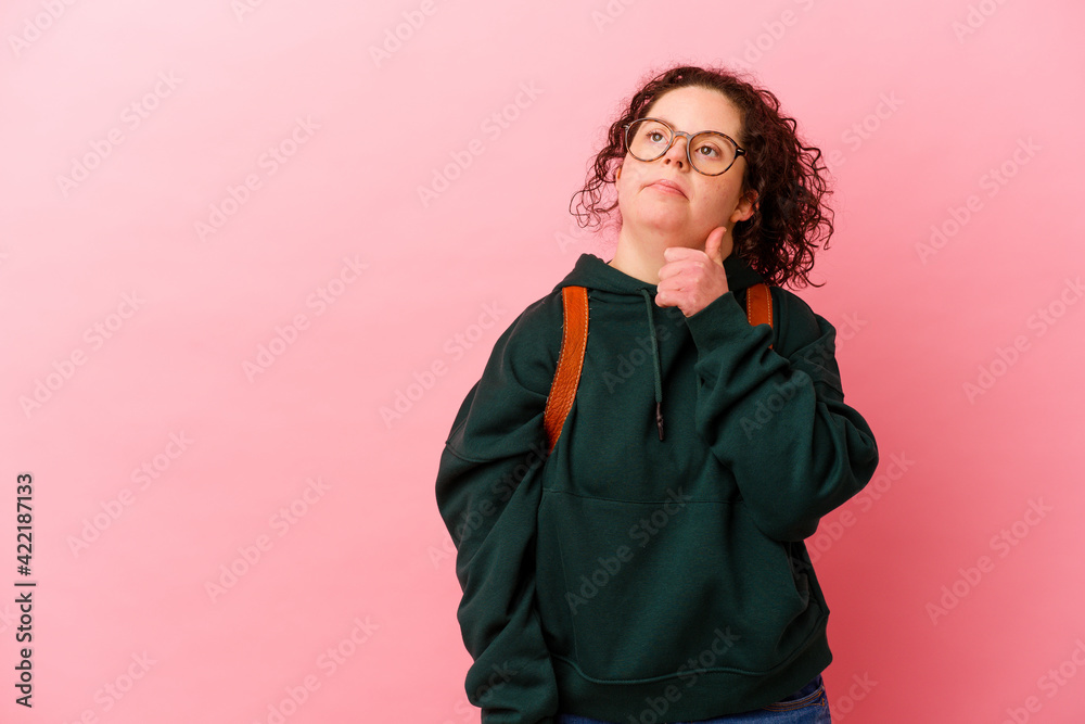 Young student woman with Down syndrome isolated on pink background looking sideways with doubtful and skeptical expression. Young student woman with Down syndrome isolated on pink background looking sideways with doubtful and skeptical expression.