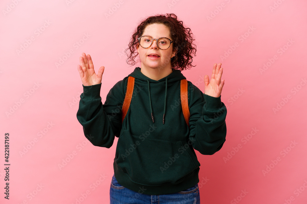 Young student woman with Down syndrome isolated on pink background receiving a pleasant surprise, excited and raising hands. Young student woman with Down syndrome isolated on pink background receiving a pleasant surprise, excited and raising hands.