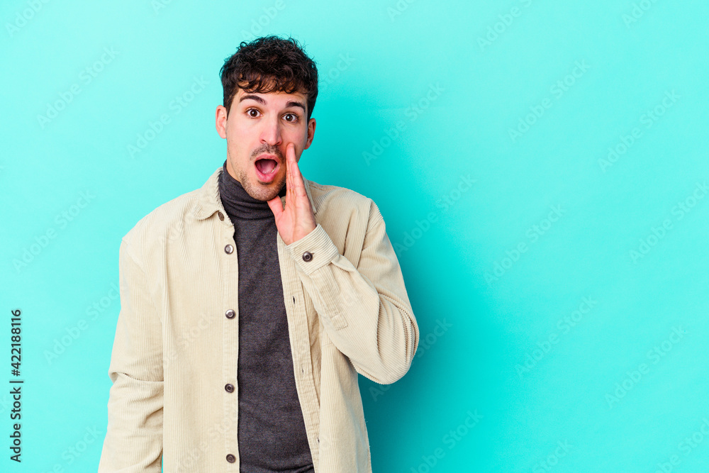 Young caucasian man isolated on blue background shouts loud, keeps eyes opened and hands tense. Young caucasian man isolated on blue background shouts loud, keeps eyes opened and hands tense.