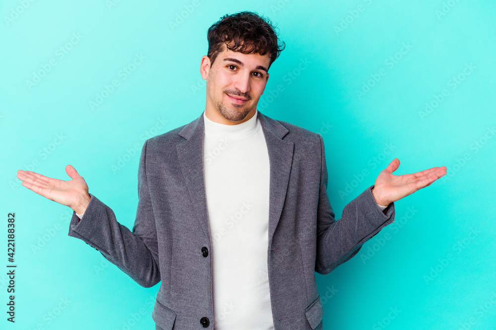 Young caucasian man isolated on blue background doubting and shrugging shoulders in questioning gesture. Young caucasian man isolated on blue background doubting and shrugging shoulders in questioning gesture.