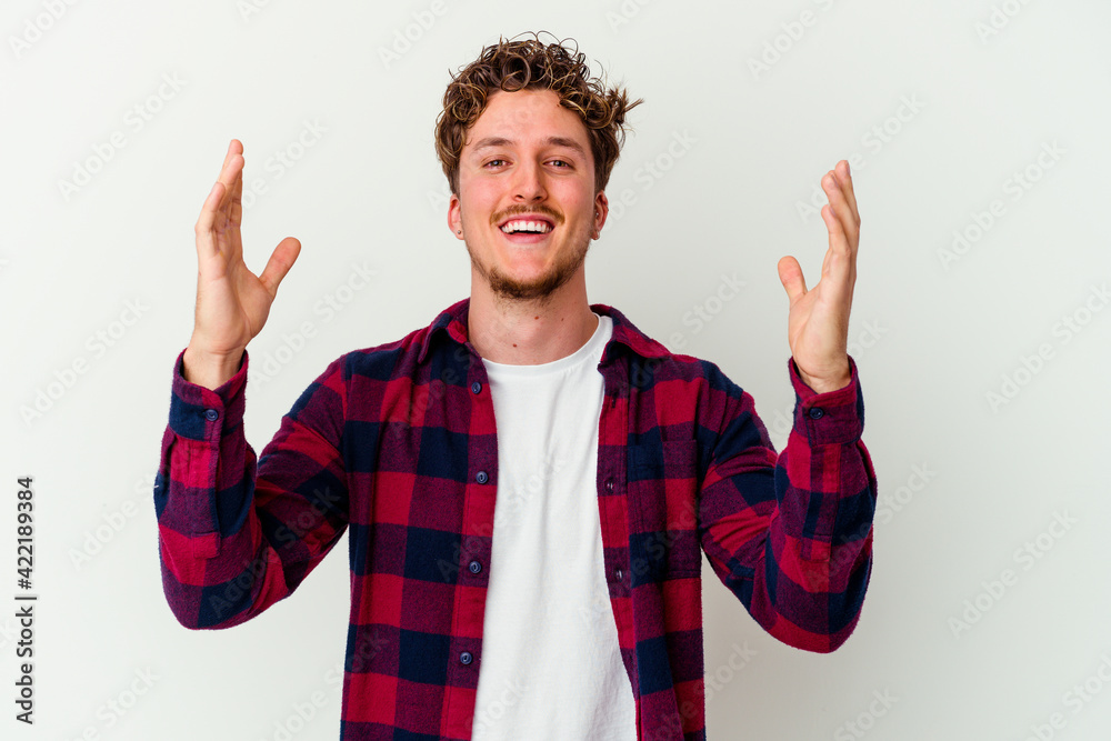 Naklejka premium Young caucasian man isolated on white background receiving a pleasant surprise, excited and raising hands.