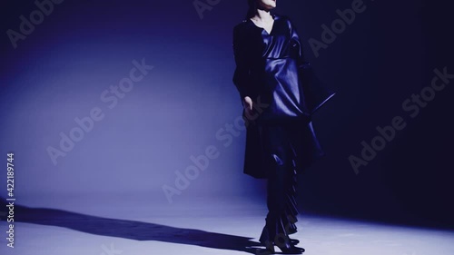Dark and long hair woman posing in the studio. Young attractive model girl wearing black dress dancing in the studio.