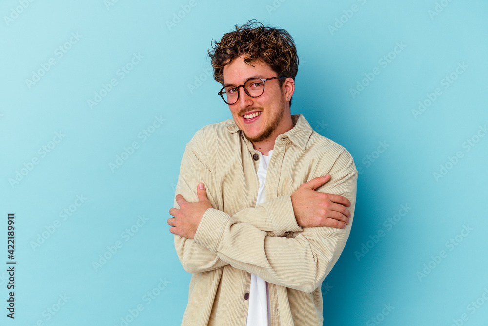 Young caucasian man wearing eyeglasses isolated on blue background hugs, smiling carefree and happy. Young caucasian man wearing eyeglasses isolated on blue background hugs, smiling carefree and happy.