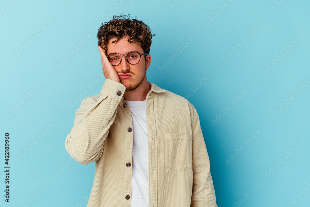Young caucasian man wearing eyeglasses isolated on blue background tired and very sleepy keeping hand on head. Young caucasian man wearing eyeglasses isolated on blue background tired and very sleepy keeping hand on head.