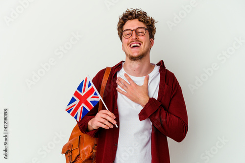 Young student man learning english isolated on white background laughs out loudly keeping hand on chest. photo