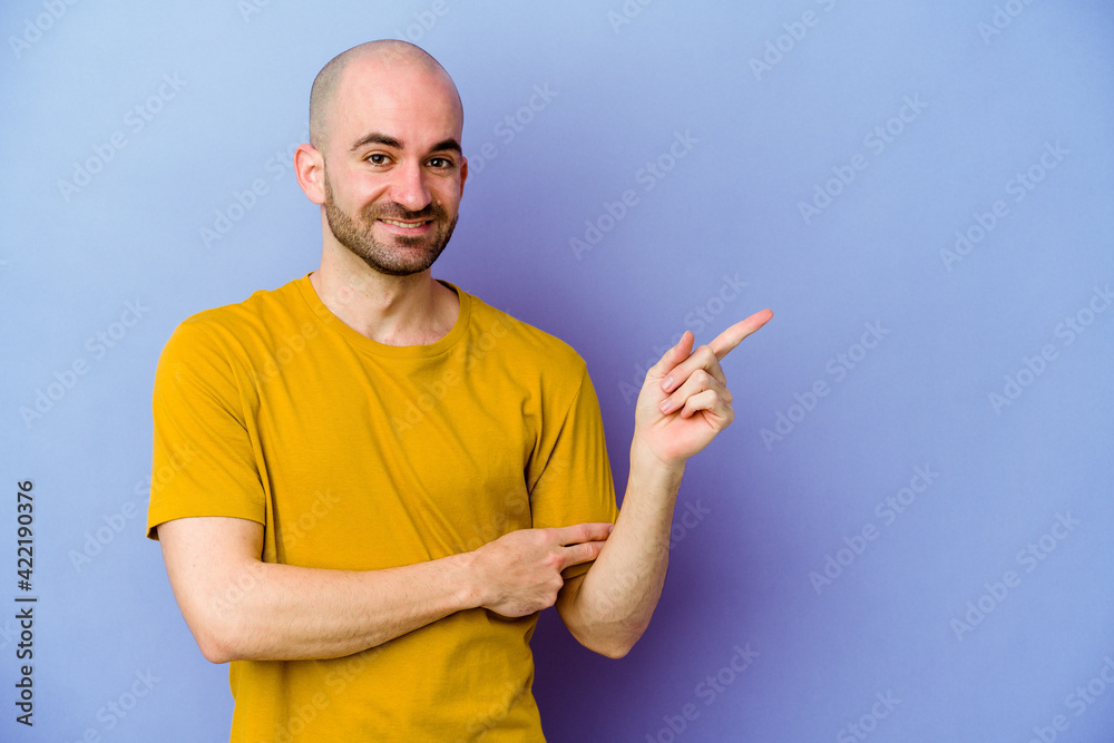 Young caucasian bald man isolated on purple background smiling cheerfully pointing with forefinger away. Young caucasian bald man isolated on purple background smiling cheerfully pointing with forefinger away.