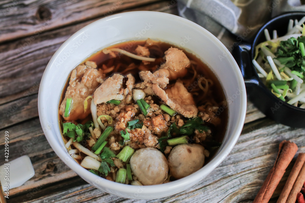 Egg noodle with pork and vegetable in five spices black soup on wooden table top view- Asian food style. Egg noodle with pork and vegetable in five spices black soup on wooden table top view- Asian food style.