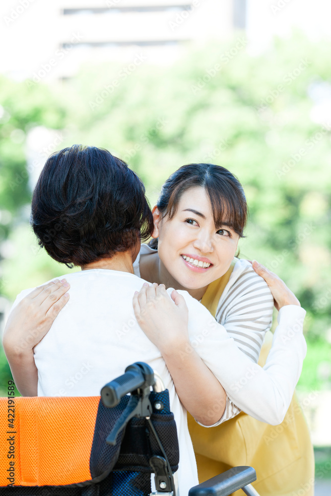 シニア女性を抱きかかえる女性介護士