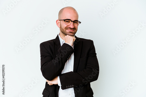 Young business caucasian bald man isolated on blue background smiling happy and confident, touching chin with hand.