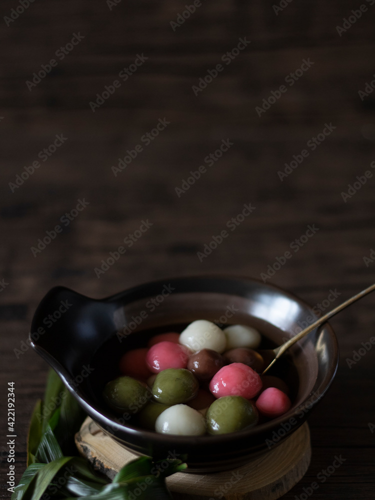 Tang Yuan (Glutinous Rice Balls) for DongZhi (Winter Solstice Festival). Colorful tang yuan side view on wooden table, dark food photography. Rice Balls close up, still life photography Tang Yuan (Glutinous Rice Balls) for DongZhi (Winter Solstice Festival). Colorful tang yuan side view on wooden table, dark food photography. Rice Balls close up, still life photography