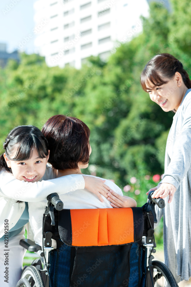  車椅子に座る祖母に抱きつく孫娘